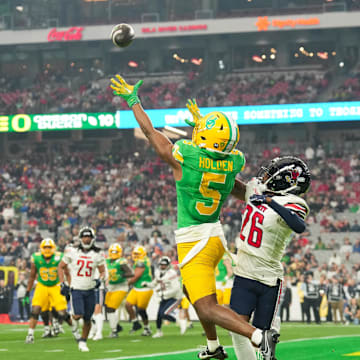 Jan 1, 2024; Glendale, AZ, USA; Oregon Ducks wide receiver Traeshon Holden (5) attempts to catch a pass as Liberty Flames cornerback Amarian Williams (26) defends him during the second quarter of the 2024 Fiesta Bowl at State Farm Stadium. Mandatory Credit: Joe Camporeale-Imagn Images