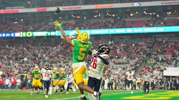 Jan 1, 2024; Glendale, AZ, USA; Oregon Ducks wide receiver Traeshon Holden (5) attempts to catch a pass as Liberty Flames cornerback Amarian Williams (26) defends him during the second quarter of the 2024 Fiesta Bowl at State Farm Stadium. Mandatory Credit: Joe Camporeale-Imagn Images