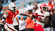 Nov 18, 2023; Miami Gardens, Florida, USA; Louisville Cardinals wide receiver Chris Bell (0) catches the football against Miami Hurricanes defensive back Damari Brown (6) during the second quarter at Hard Rock Stadium. Mandatory Credit: Sam Navarro-Imagn Images