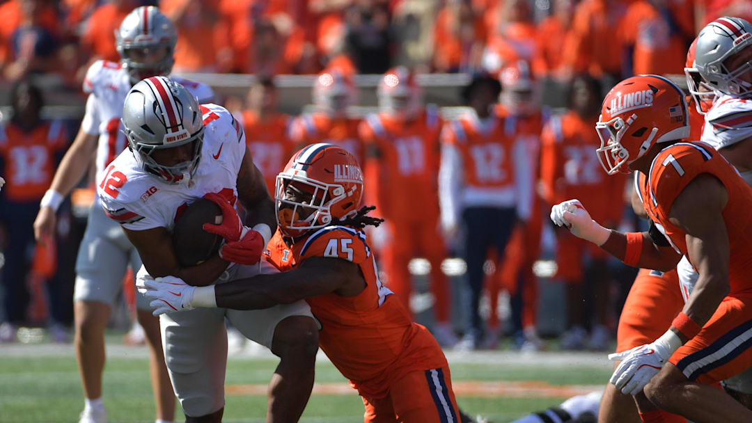 Oct 11, 2025; Champaign, Illinois, USA; Ohio State Buckeyes running back CJ Donaldson Jr. (12) is tackled by Illinois Fighting Illini linebacker Malachi Hood (45) during the first quarter at Memorial Stadium. Mandatory Credit: Ron Johnson-Imagn Images