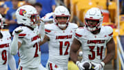 Sep 27, 2025; Pittsburgh, Pennsylvania, USA;  Louisville Cardinals defensive back Corey Gordon (24) and linebacker Kalib Perry (12) celebrate an interception by linebacker TJ Quinn (34) against the Pittsburgh Panthers during the fourth quarter at Acrisure Stadium. Mandatory Credit: Charles LeClaire-Imagn Images