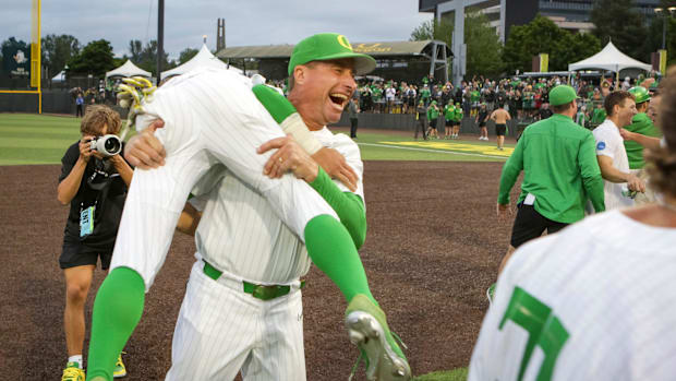 Oregon head coach Mark Wasikowski carries infielder Rikuu Nishida as the Oregon Ducks defeated Oral Roberts University 9-8 in