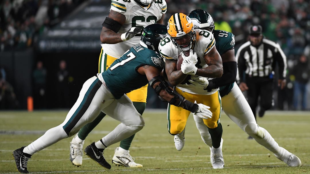 Jan 12, 2025; Philadelphia, Pennsylvania, USA; Green Bay Packers running back Josh Jacobs (8) rushes the ball against Philadelphia Eagles defensive tackle Milton Williams (93) and linebacker Nakobe Dean (17) during the first half in an NFC wild card game at Lincoln Financial Field. Mandatory Credit: Eric Hartline-Imagn Images