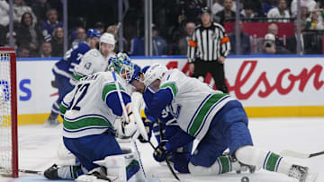 Jan 11, 2025; Toronto, Ontario, CAN; Vancouver Canucks goaltender Kevin Lankinen (32) follows a loose puck as defenseman Tyler Myers (57) clears Toronto Maple Leafs forward Auston Matthews (34) away from the front of the net during the third period at Scotiabank Arena. Mandatory Credit: John E. Sokolowski-Imagn Images