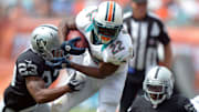 Miami Dolphins running back Reggie Bush (22) eludes Oakland Raiders cornerback Joseph Hanson (23) and linebacker Roland McClain (55) to score on a 23-yard touchdown run at Sun Life Stadium in 2012.