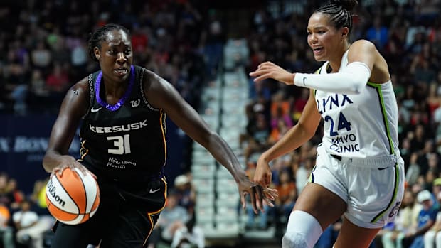 Connecticut Sun center Tina Charles drives the ball in a black uniform past a defender in a white uniform