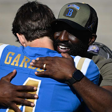 Nov 30, 2024; Pasadena, California, USA; UCLA Bruins head coach DeShaun Foster hugs UCLA Bruins quarterback Ethan Garbers (4) during pregame “senior day” ceremonies before playing the  Fresno State Bulldogs at Rose Bowl. Mandatory Credit: Robert Hanashiro-Imagn Images