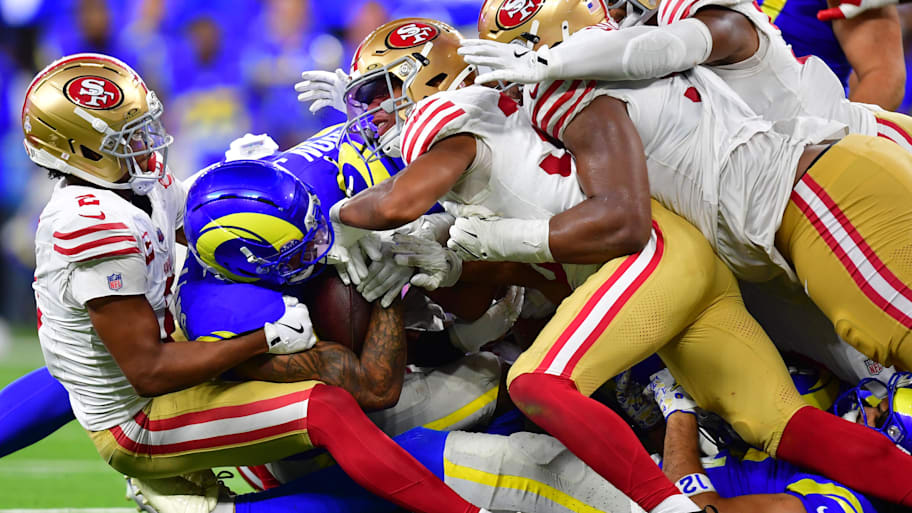 A gang of 49ers players tackles a Rams ballcarrier