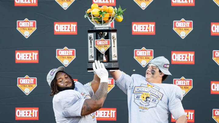 Jan 2, 2023; Orlando, FL, USA; LSU Tigers defensive tackle Jacobian Guillory (90) and offensive lineman Will Campbell (66) hold the Citrus Bowl trophy after the game against the Purdue Boilermakers at Camping World Stadium. Mandatory Credit: Matt Pendleton-USA TODAY Sports