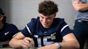 Penn State quarterback Drew Allar signs a poster before the start of the annual Blue-White Game at Beaver Stadium. 