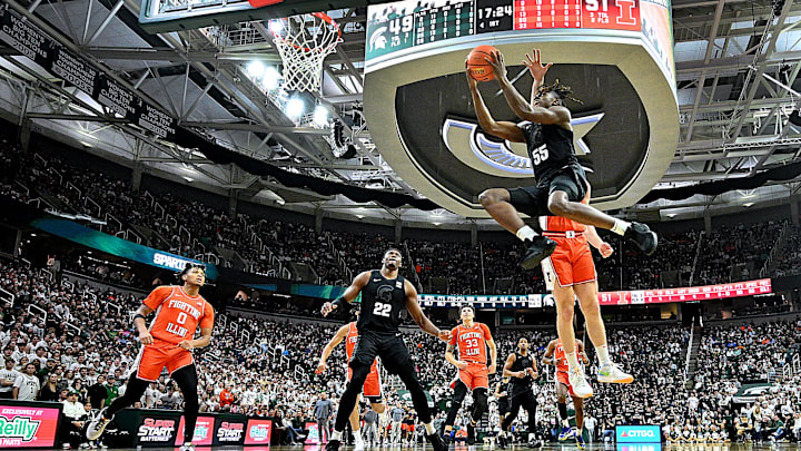 Feb 10, 2024; East Lansing, Michigan, USA;  Michigan State Spartans forward Coen Carr (55) flies past Illinois Fighting Illini defenders for a layup from the wing during the second half at Jack Breslin Student Events Center. Mandatory Credit: Dale Young-Imagn Images