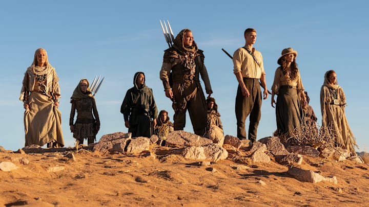 A group of Aiel with Rand (Josha Stradowski), Moiraine (Rosamund Pike) and Lan (Daniel Henney), which includes Bair (Nukâka Coster-Waldau) and Rhuarc (Björn Landberg).