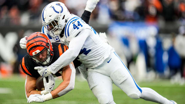 Colts linebacker Zaire Franklin (all-white uniform with blue trim) makes a tackle to a player (orange/black uniform). 