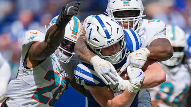 Colts tight end Tyler Warren (blue and white jersey) tries to run away from defenders.