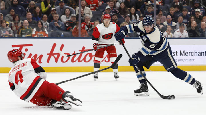 Mar 31, 2026; Columbus, Ohio, USA; Columbus Blue Jackets center Sean Monahan (23) wrists a shot on goal as Carolina Hurricanes defenseman Shayne Gostisbehere (4) defends during the second period at Nationwide Arena. Mandatory Credit: Russell LaBounty-Imagn Images