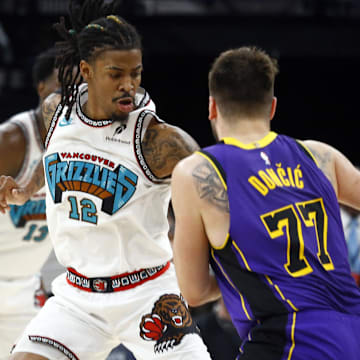 Mar 29, 2025: Memphis, Tennessee, USA; Memphis Grizzlies guard Ja Morant (12) defends as Los Angeles Lakers guard Luka Doncic (77) drives to the basket during the fourth quarter at FedExForum. Mandatory Credit: Petre Thomas-Imagn Images