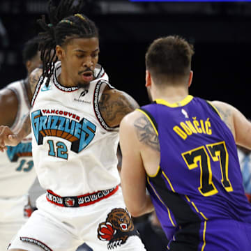 Mar 29, 2025; Memphis, Tennessee, USA; Memphis Grizzlies guard Ja Morant (12) defends as Los Angeles Lakers guard Luka Doncic (77) drives to the basket during the fourth quarter at FedExForum. Mandatory Credit: Petre Thomas-Imagn Images
