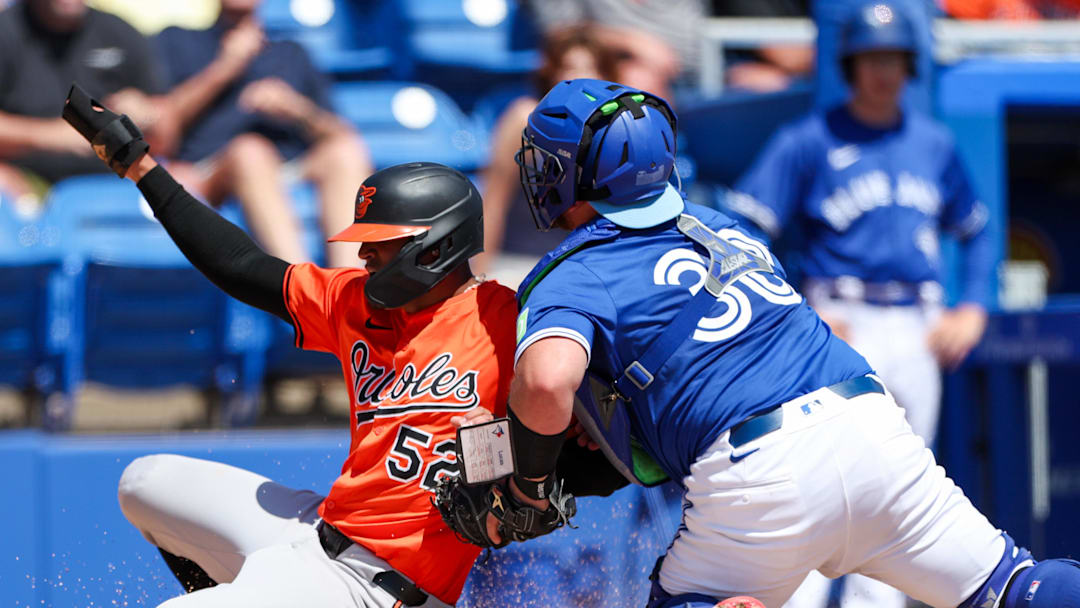 Mar 13, 2025; Dunedin, Florida, USA; Toronto Blue Jays catcher Alejandro Kirk (30) tags out Baltimore Orioles shortstop Luis Vasquez (52) in the second inning during spring training at TD Ballpark. Mandatory Credit: Nathan Ray Seebeck-Imagn Images
