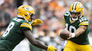 Green Bay Packers quarterback Jordan Love (10) hand the ball off to running back Josh Jacobs.