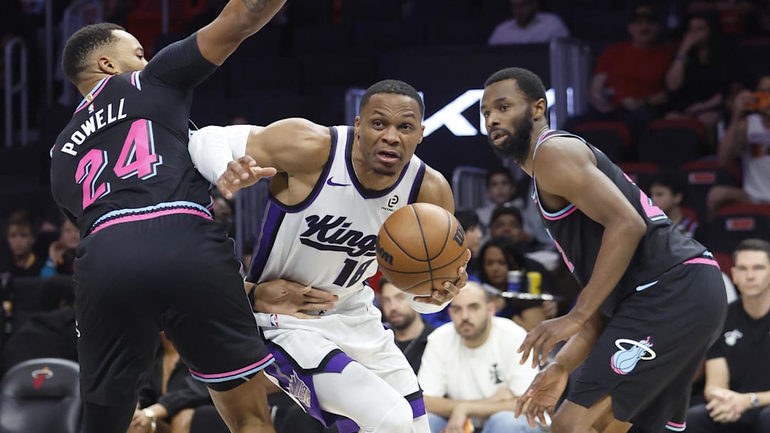 Dec 6, 2025; Miami, Florida, USA;  Sacramento Kings guard Russell Westbrook (18) is defended by Miami Heat guard Norman Powell (24) and forward Andrew Wiggins (22) during the second half at Kaseya Center. Mandatory Credit: Rhona Wise-Imagn Images