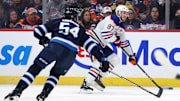Apr 13, 2025; Winnipeg, Manitoba, CAN; Edmonton Oilers center Connor McDavid (97) eludes Winnipeg Jets defenseman Dylan Samberg (54) in the first period at Canada Life Centre. Mandatory Credit: James Carey Lauder-Imagn Images