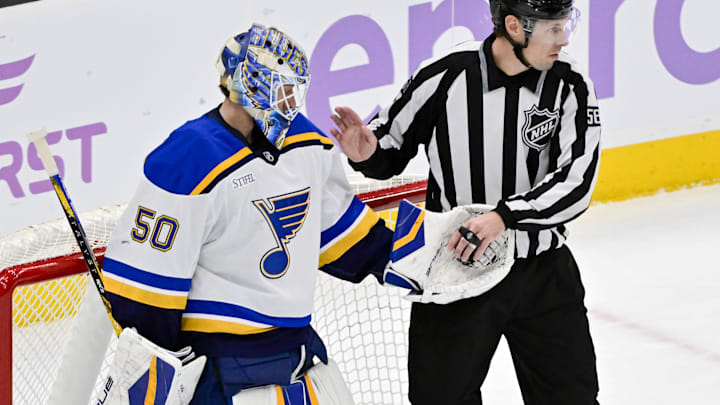 Jan 18, 2025; Salt Lake City, Utah, USA; St. Louis Blues goalie Jordan Binnington (50) hands the puck to linesperson Ryan Gibbons (58) after a block against the Utah Hockey Club during second period at the Delta Center. Mandatory Credit: Christopher Creveling-Imagn Images