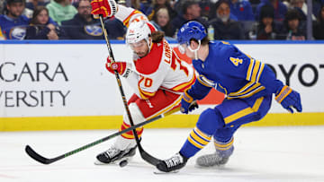 Nov 9, 2024; Buffalo, New York, USA;  Calgary Flames left wing Ryan Lomberg (70) and Buffalo Sabres defenseman Bowen Byram (4) go after a loose puck during the third period at KeyBank Center. Mandatory Credit: Timothy T. Ludwig-Imagn Images