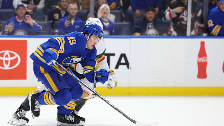 Mar 3, 2026; Buffalo, New York, USA;  Buffalo Sabres center Peyton Krebs (19) and Vegas Golden Knights defenseman Shea Theodore (27) skate for a loose puck during the third period at KeyBank Center. Mandatory Credit: Timothy T. Ludwig-Imagn Images