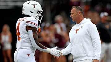 Oct 25, 2025; Starkville, Mississippi, USA; Texas Longhorns head coach Steve Sarkisian (right) talks with Texas Longhorns running back CJ Baxter Jr. (4) during warm ups prior to the game against the Mississippi State Bulldogs at Davis Wade Stadium at Scott Field. Mandatory Credit: Petre Thomas-Imagn Images