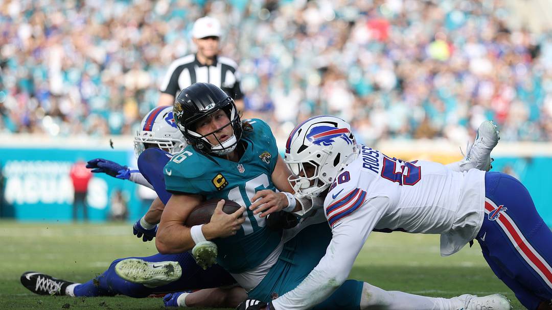 Jacksonville Jaguars quarterback Trevor Lawrence (16) is tackled by Buffalo Bills defensive end Greg Rousseau (50) during the second half in an AFC Wild Card Round game at EverBank Stadium. 