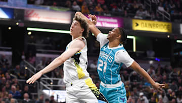 Dec 8, 2024; Indianapolis, Indiana, USA; Charlotte Hornets guard Isaiah Wong (21) fouls Indiana Pacers forward Johnny Furphy (12) on a shot attempt during the first half at Gainbridge Fieldhouse. Mandatory Credit: Robert Goddin-Imagn Images 
