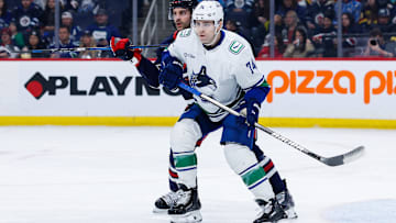 Jan 14, 2025; Winnipeg, Manitoba, CAN;  Vancouver Canucks forward Jake DeBrusk (74) and Winnipeg Jets defenseman Dylan DeMelo (2) look for the puck during the first period at Canada Life Centre. Mandatory Credit: Terrence Lee-Imagn Images