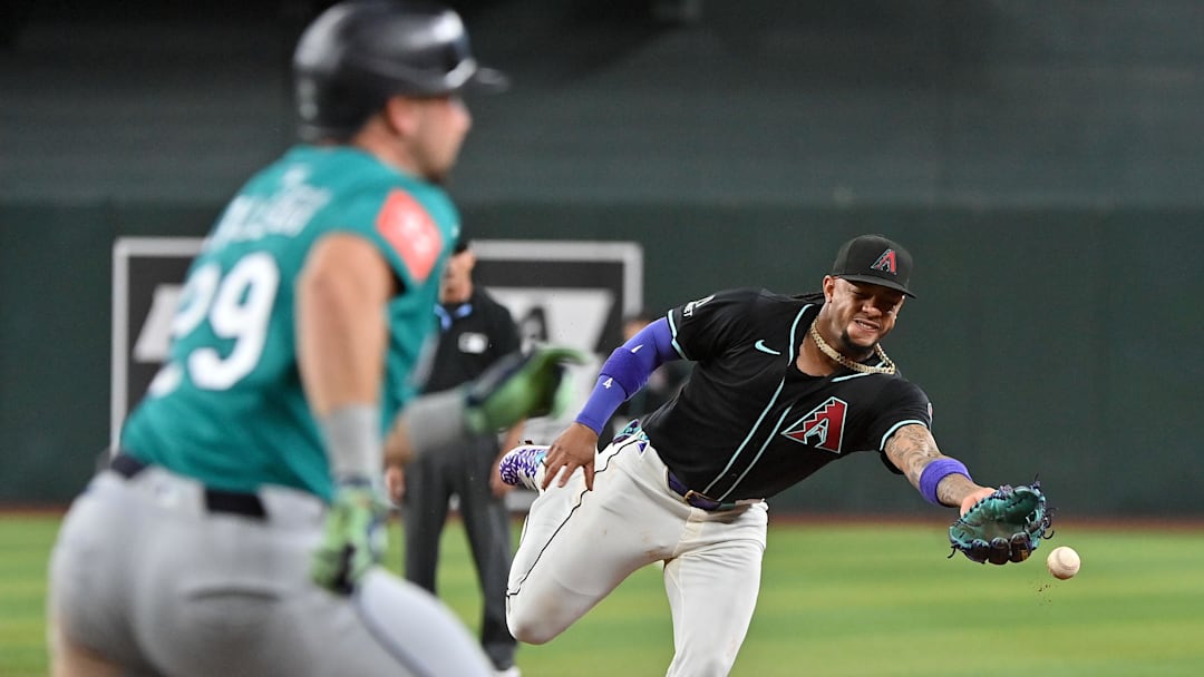 Jun 11, 2025; Phoenix, Arizona, USA;  Arizona Diamondbacks second base Ketel Marte (4) tosses the ball to first baseman as Seattle Mariners catcher Cal Raleigh (29) beats him in the third inning at Chase Field. Mandatory Credit: Matt Kartozian-Imagn Images