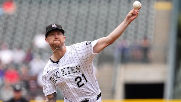 Kyle Freeland pitching for the Colorado Rockies in white pinstripe uniforms. 