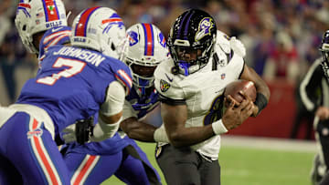 Baltimore Ravens quarterback Lamar Jackson tries to avoid Buffalo Bills cornerback Dorian Strong and cornerback Taron Johnson