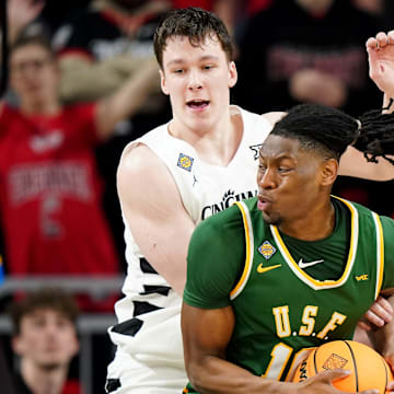 San Francisco Dons forward Jonathan Mogbo (10) spins toward the basket as Cincinnati Bearcats guard Simas Lukosius (41) defends in the second half of a college basketball game in the National Invitation Tournament, Wednesday, March 20, 2024, at Fifth Third Arena in Cincinnati.