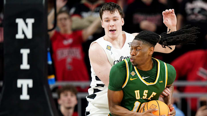 San Francisco Dons forward Jonathan Mogbo (10) spins toward the basket as Cincinnati Bearcats guard Simas Lukosius (41) defends in the second half of a college basketball game in the National Invitation Tournament, Wednesday, March 20, 2024, at Fifth Third Arena in Cincinnati.