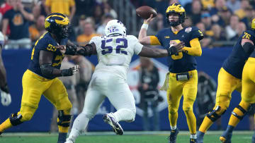 Dec 31, 2022; Glendale, Arizona, USA; Michigan Wolverines quarterback J.J. McCarthy (9) makes a throw under pressure by TCU Horned Frogs defensive lineman Damonic Williams (52) in the first half of the 2022 Fiesta Bowl at State Farm Stadium. Mandatory Credit: Joe Camporeale-USA TODAY Sports