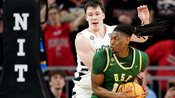 San Francisco Dons forward Jonathan Mogbo (10) spins toward the basket as Cincinnati Bearcats guard Simas Lukosius (41) defends in the second half of a college basketball game in the National Invitation Tournament, Wednesday, March 20, 2024, at Fifth Third Arena in Cincinnati.