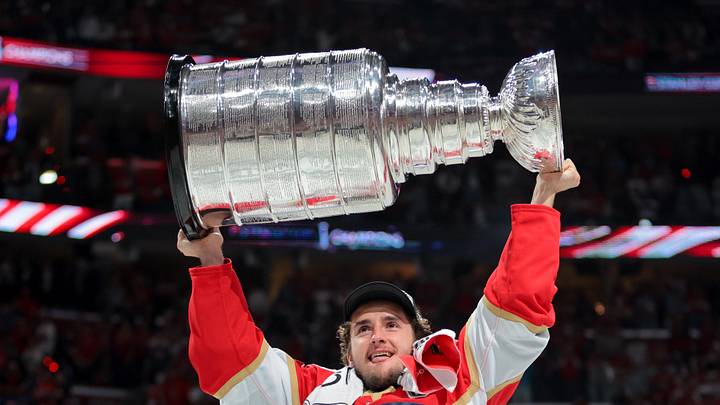 Jun 17, 2025; Sunrise, Florida, USA; Florida Panthers right wing Mackie Samoskevich (25) hoists the Stanley Cup after winning game six of the 2025 Stanley Cup Final against the Edmonton Oilers at Amerant Bank Arena. Mandatory Credit: Sam Navarro-Imagn Images