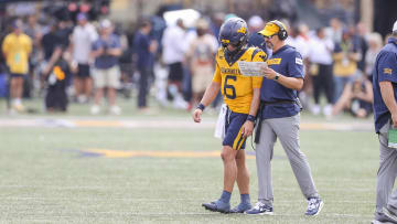 Aug 31, 2024; Morgantown, West Virginia, USA; West Virginia Mountaineers head coach Neal Brown talks with West Virginia Mountaineers quarterback Garrett Greene (6) during the second quarter against the Penn State Nittany Lions at Mountaineer Field at Milan Puskar Stadium. 