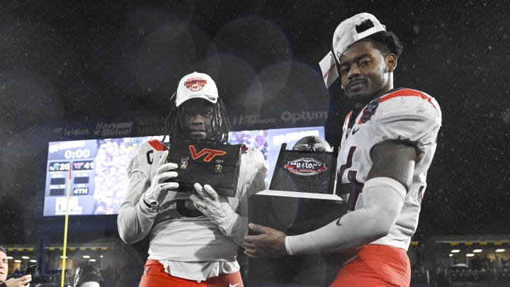 Dec 27, 2023; Annapolis, MD, USA;  Virginia Tech Hokies defensive lineman Norell Pollard (3) hoist the lunch pail as  linebacker Alan Tisdale (34) holds the the Military Bowl trophy and after the game against the Tulane Green Wave at Navy-Marine Corps Memorial Stadium. Mandatory Credit: Tommy Gilligan-USA TODAY Sports