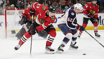 Dec 1, 2024; Chicago, Illinois, USA; Columbus Blue Jackets right wing Kevin Labanc (62) and Chicago Blackhawks center Philipp Kurashev (23) go for the puck during the second period at United Center. Mandatory Credit: David Banks-Imagn Images