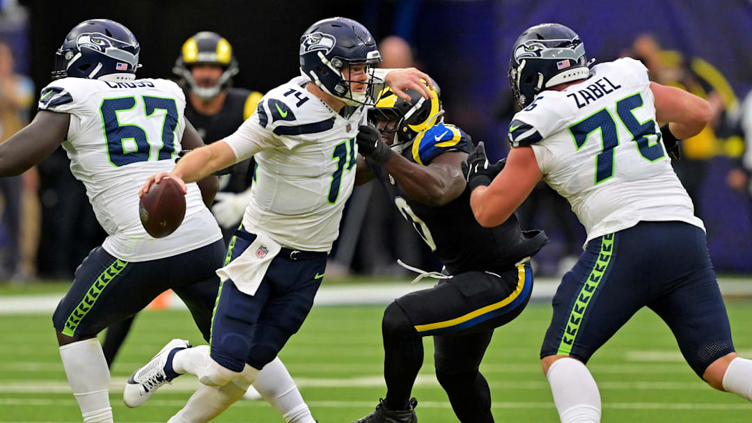 Nov 16, 2025; Inglewood, California, USA; Seattle Seahawks quarterback Sam Darnold (14) runs away from Los Angeles Rams linebacker Byron Young (0) during the second half at SoFi Stadium. Mandatory Credit: Jayne Kamin-Oncea-Imagn Images