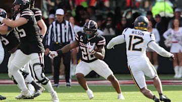 Nov 30, 2024; Lubbock, Texas, USA;  Texas Tech Red Raiders running back Tahj Brooks (28) runs the ball against West Virginia Mountaineers defensive back Anthony Wilson Jr. (12) in the second half at Jones AT&T Stadium and Cody Campbell Field. Mandatory Credit: Michael C. Johnson-Imagn Images