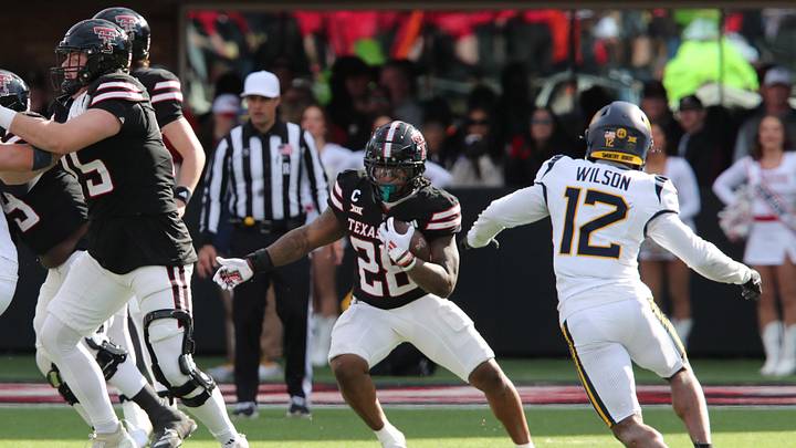 Nov 30, 2024; Lubbock, Texas, USA;  Texas Tech Red Raiders running back Tahj Brooks (28) runs the ball against West Virginia Mountaineers defensive back Anthony Wilson Jr. (12) in the second half at Jones AT&T Stadium and Cody Campbell Field. Mandatory Credit: Michael C. Johnson-Imagn Images
