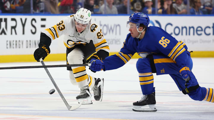 Mar 25, 2026; Buffalo, New York, USA;  Buffalo Sabres center Noah Ostlund (86) and Boston Bruins center Fraser Minten (93) go after a loose puck during the third period at KeyBank Center. Mandatory Credit: Timothy T. Ludwig-Imagn Images