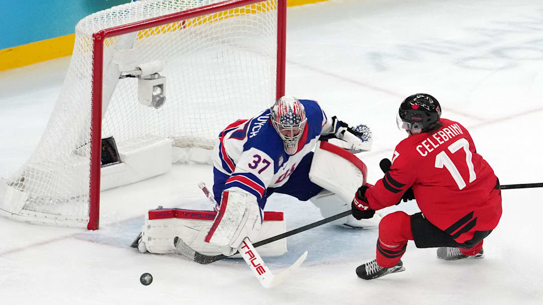 Feb 22, 2026; Milan, Italy; Connor Hellebuyck of the United States battles for the puck against Macklin Celebrini of Canada during the men's ice hockey gold medal game during the Milano Cortina 2026 Olympic Winter Games at Milano Santagiulia Ice Hockey Arena. Mandatory Credit: James Lang-Imagn Images