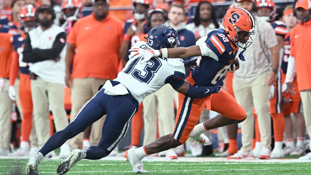 Nov 23, 2024; Syracuse, New York, USA; Syracuse Orange wide receiver Darrell Gill Jr. (82) breaks a tackle by Connecticut Huskies defensive back Cam Chadwick (13) in the first quarter at the JMA Wireless Dome. Mandatory Credit: Mark Konezny-Imagn Images
