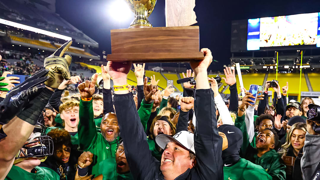 Basha head coach Chris McDonald holds up the Open Division Championship trophy. 